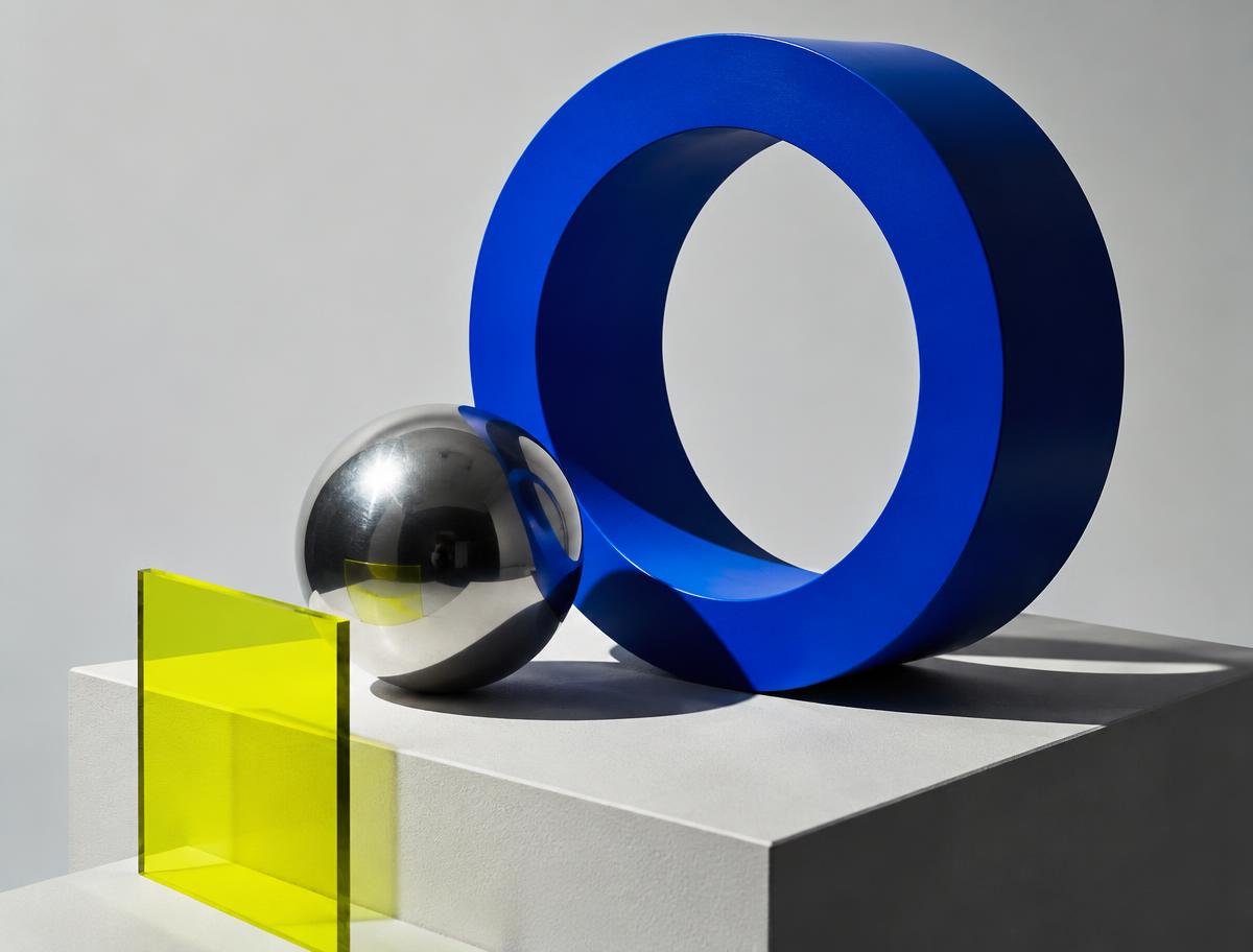 Bold blue sculptural form and reflective sphere in an editorial composition